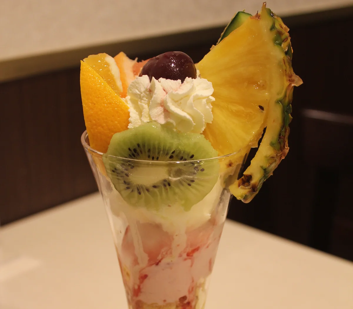 雪印パーラー札幌本店のフルーツパフェ。果物とホイップクリームが載るグラス